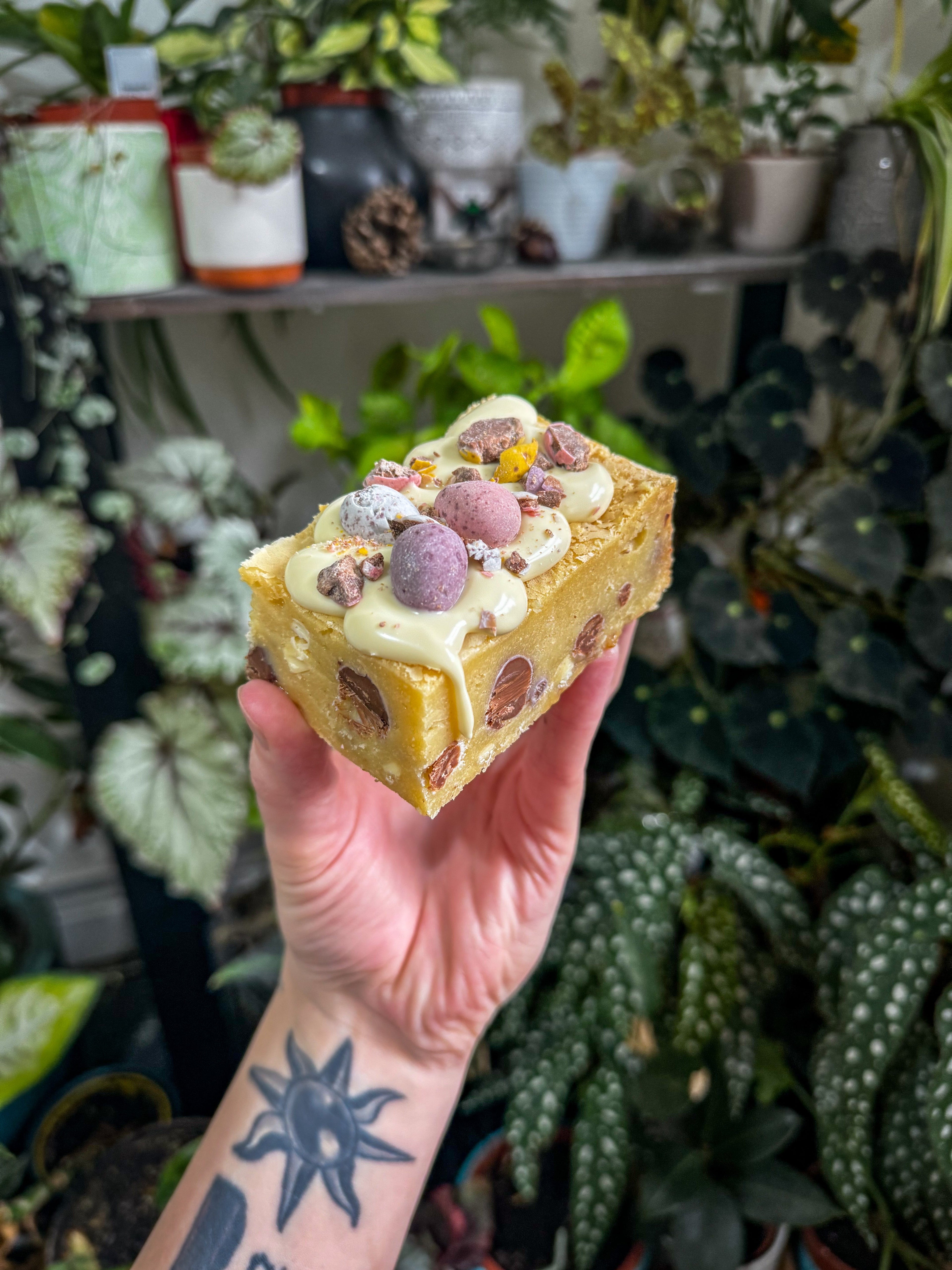 Thick mini egg & white chocolate blondie with a fudgy centre, topped with white chocolate, mini eggs and crushed chocolate piece